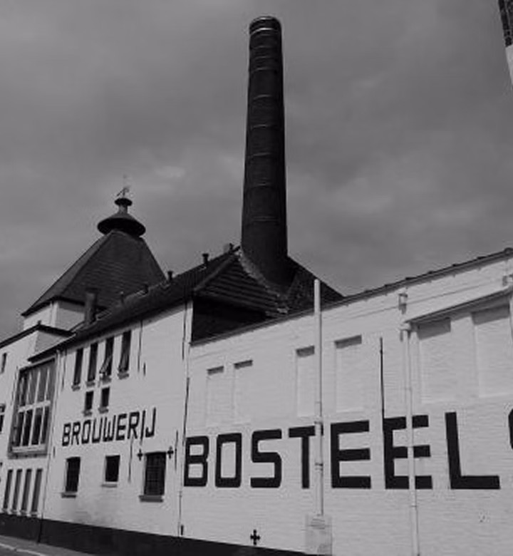 Black and white view of the Brouwerij Bosteels building with its tall chimney and painted brewery name