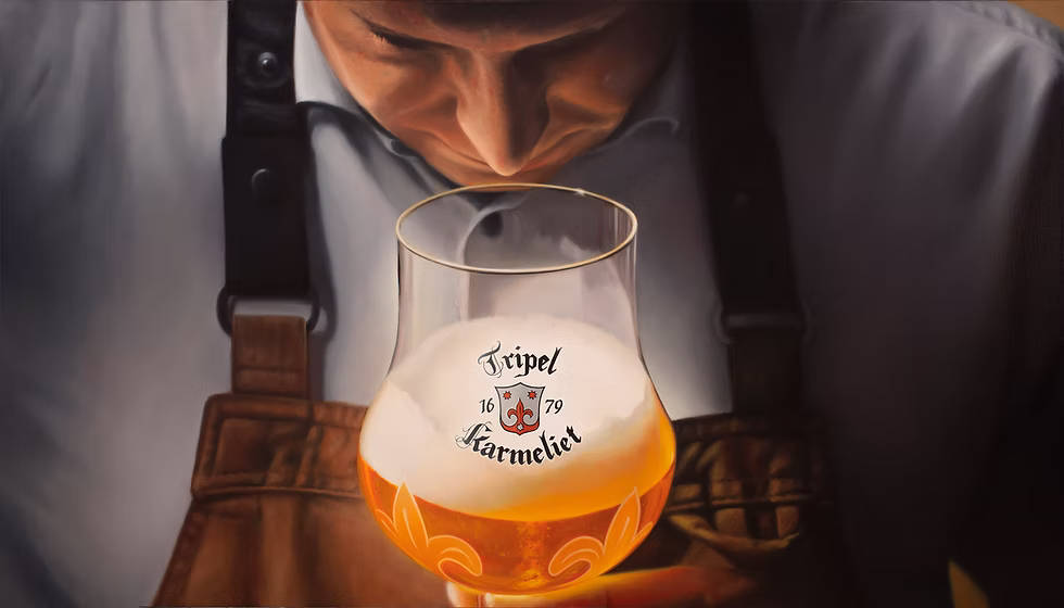 Tripel Karmeliet glass filled with golden beer and a creamy head, in front of a brewer’s leather apron